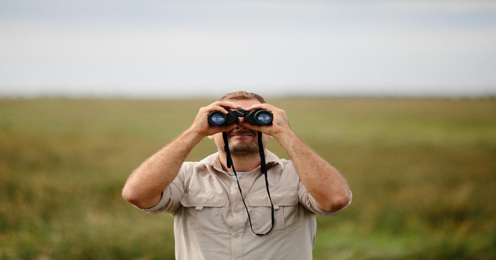 Man in field using 10x42 binoculars