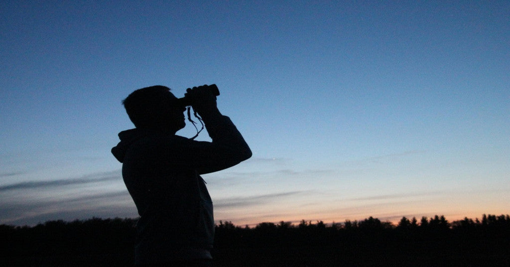 Man at dusk using binoculars for stargazing
