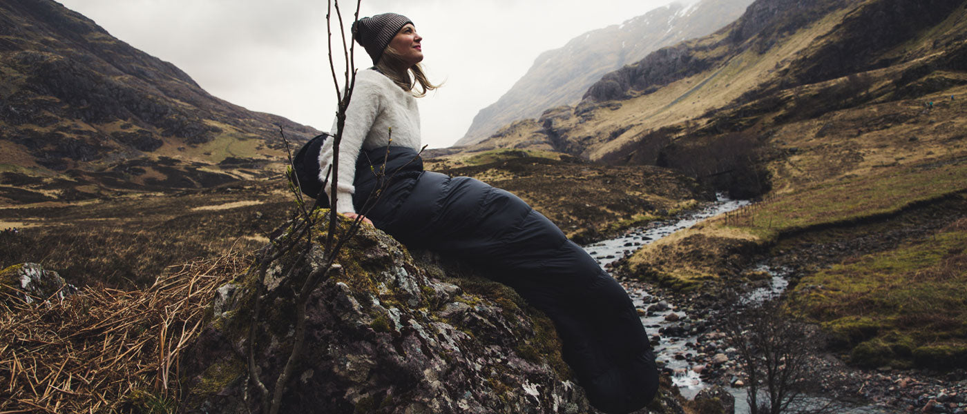 Woman in sleeping bag sitting on rock