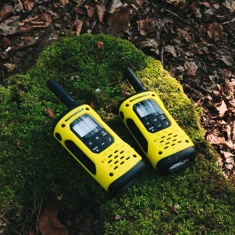 Two yellow walkie talkies on moss-covered log