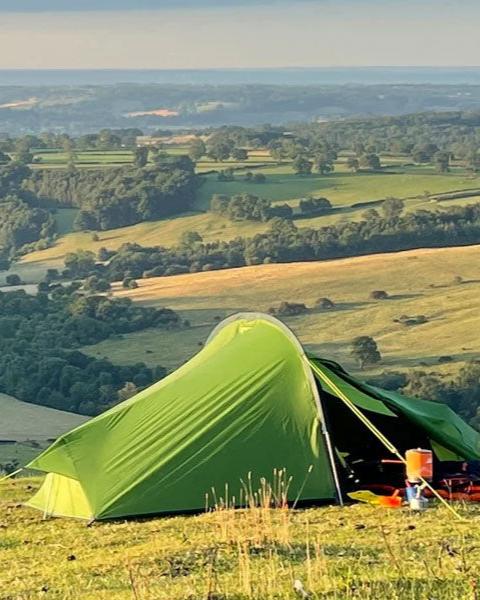 Green tent with rolling hills in background